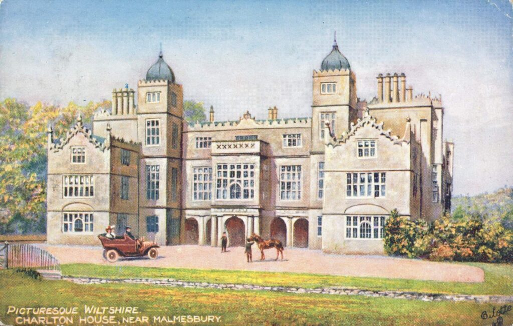 A vintage postcard depicting Charlton House, a large historic mansion located near Malmesbury in Wiltshire. The house features a grand facade with multiple stories, tall windows, and decorative gables. The building has two prominent towers with domed roofs, adding to its stately appearance. In front of the house, there is a driveway where a vintage car with two passengers is parked, and a person is holding a horse nearby. The scene is set against a backdrop of lush greenery, with trees and a well-kept lawn. The text at the bottom of the postcard reads, "Picturesque Wiltshire, Charlton House, near Malmesbury.